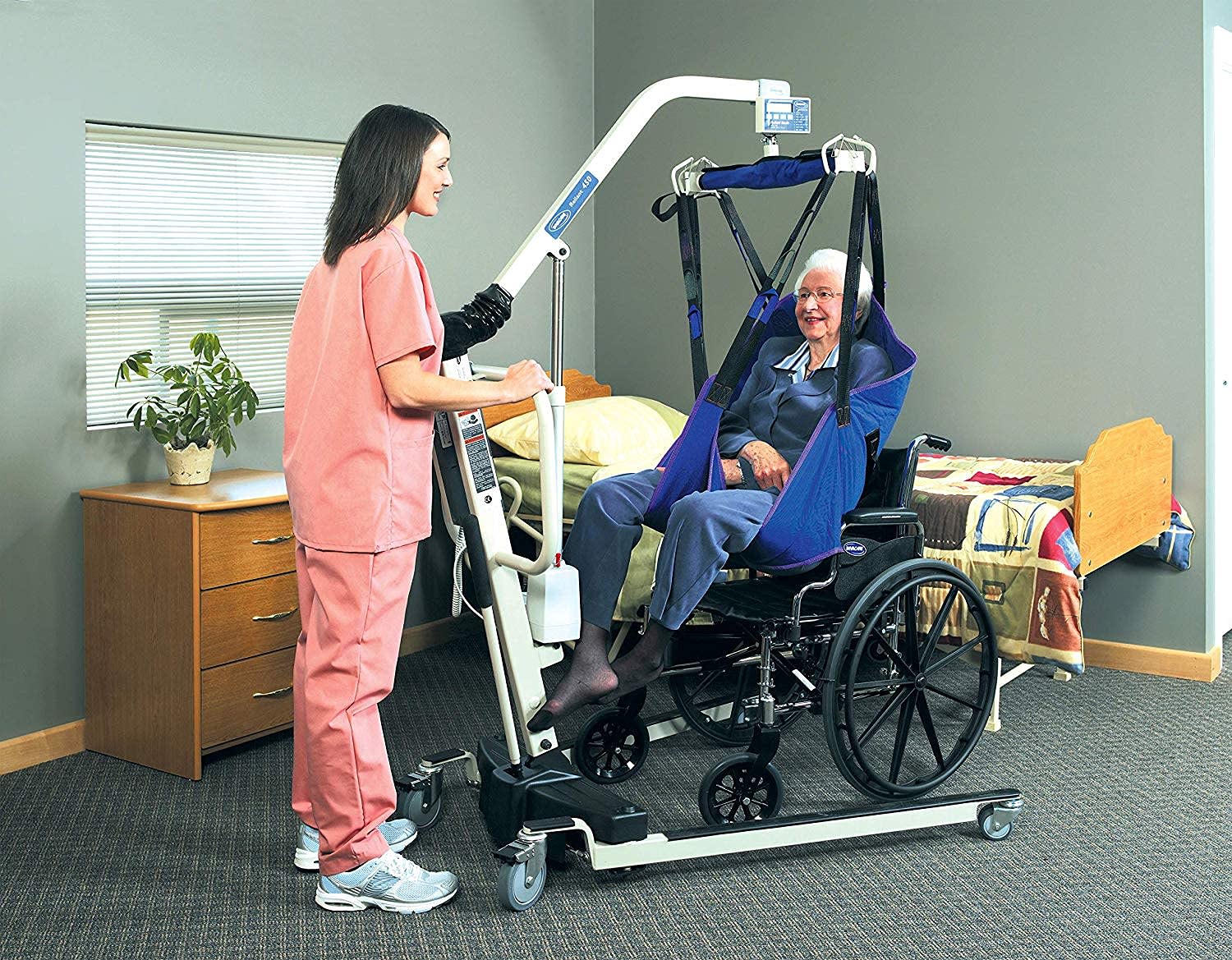 A woman assisting a user with the Invacare Reliant Electric Patient Lift, item RPL450-1 in a care setting. 